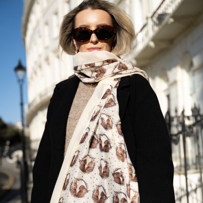 Blonde lady standing outside white buildings in chelsea holding a dark tan leather bag and wearing a hand printed bunny rabbit print scarf with sunglasses on