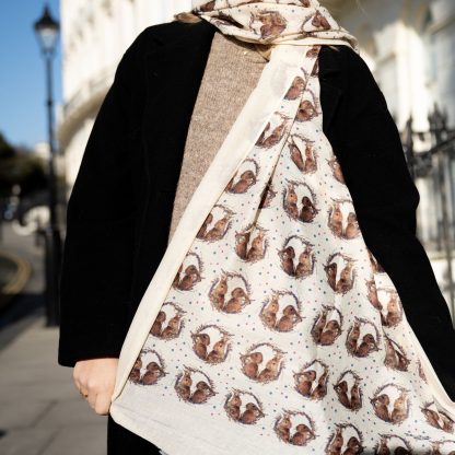 Blonde lady standing outside white buildings in chelsea holding a dark tan leather bag and wearing a hand printed bunny rabbit print scarf with sunglasses on