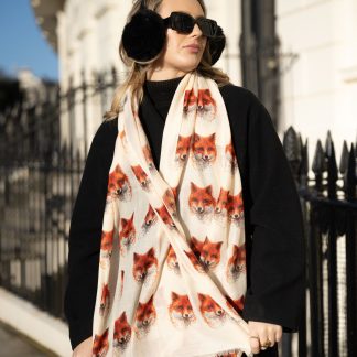 Blonde lady standing outside white buildings in chelsea, wearing an all back outfit, taupe jumper and a hand printed foxes heads design scarf with black sunglasses on