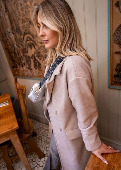 Blonde female model wearing a beautiful crossbody bag strap printed with a music notes design in a rustic restaurant