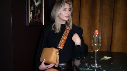 Blonde female model wearing a beautiful crossbody bag strap printed with a retro heart design in a cocktail bar