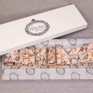 an open gift box lined with branded tissue paper showing a replacement bag strap printed with various woodland animals