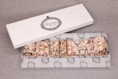 an open gift box lined with branded tissue paper showing a replacement bag strap printed with various woodland animals