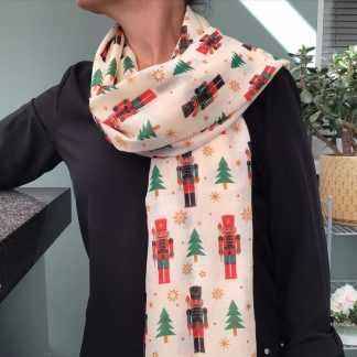 cream coloured scarf featuring a Christmas design of nutcracker soldiers in red, green & black