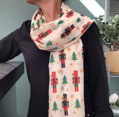 cream coloured scarf featuring a Christmas design of nutcracker soldiers in red, green & black