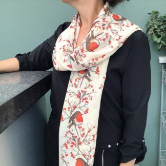 Cream coloured scarf being worn over the shoulder printed with a Christmas robin design