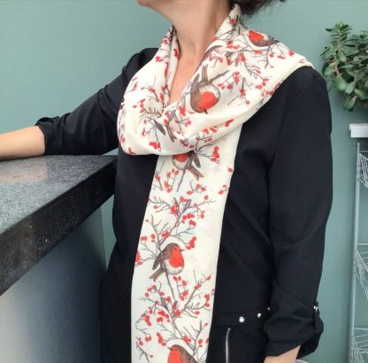 Cream coloured scarf being worn over the shoulder printed with a Christmas robin design