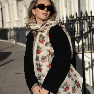 Blonde lady standing outside white buildings in chelsea, wearing an all back outfit, taupe jumper and a hand printed bows and pinecones design scarf with black sunglasses on