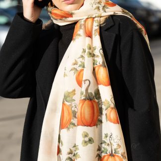 Blonde lady standing outside white buildings in chelsea, wearing an all back outfit, taupe jumper and a hand printed pumpkins design scarf with black sunglasses on