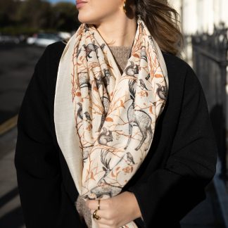 Blonde lady standing outside white buildings in chelsea, wearing an all back outfit, taupe jumper and a hand printed woodland animals design scarf with black sunglasses on