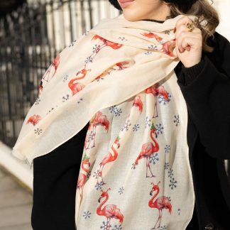 Blonde lady standing outside white buildings in chelsea, wearing an all back outfit, taupe jumper and a hand printed festive flamingos design scarf with black sunglasses on