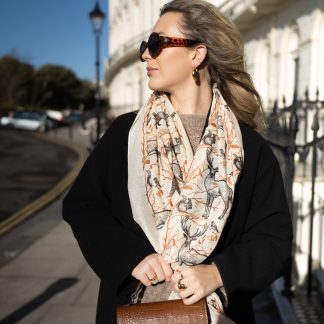 Blonde lady standing outside white buildings in chelsea, wearing an all back outfit, taupe jumper and a hand printed woodland animals design scarf with black sunglasses on