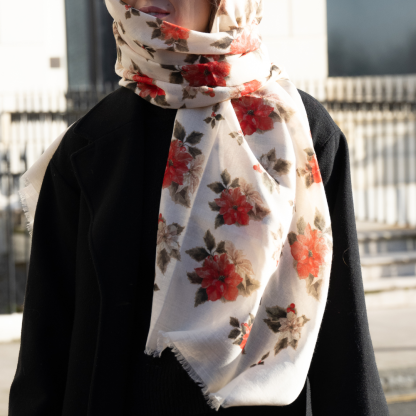 Blonde lady standing outside white buildings in chelsea, wearing an all back outfit, taupe jumper and a hand printed poinsettia design scarf with black sunglasses on