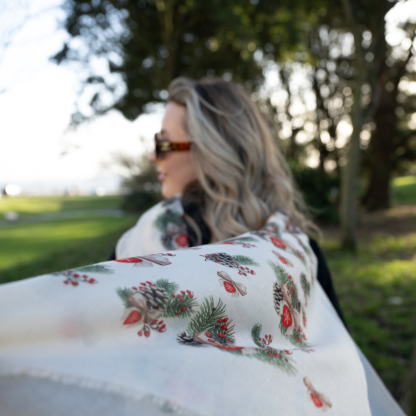 Blonde lady standing outside white buildings in chelsea, wearing an all back outfit, taupe jumper and a hand printed bows and pinecones design scarf with black sunglasses on