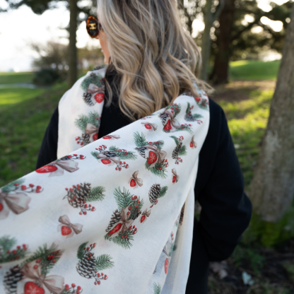 Blonde lady standing outside white buildings in chelsea, wearing an all back outfit, taupe jumper and a hand printed bows and pinecones design scarf with black sunglasses on